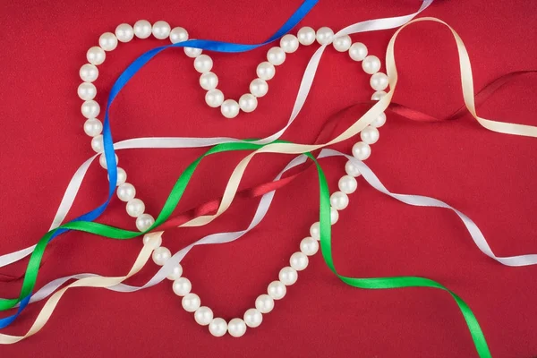 Beads in the form of heart and multi-colored satin ribbons. — Stock Photo, Image