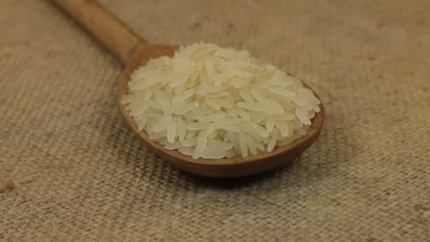 Primer plano, rotación cuchara con una pila de granos de arroz acostado en la arpillera . — Vídeo de stock