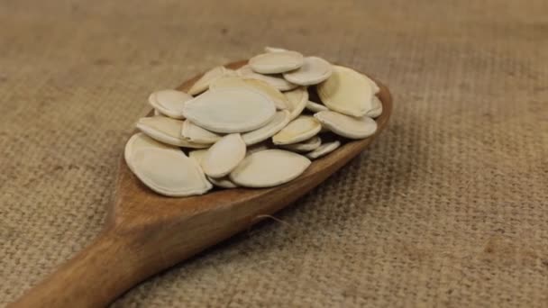 Primer plano, rotación cuchara con una pila de semillas de calabaza que se encuentran en la arpillera . — Vídeo de stock