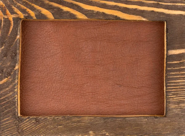 Rectangular frame made of dark wood lies on brown natural leather. Texture of a tree. — Stock Photo, Image