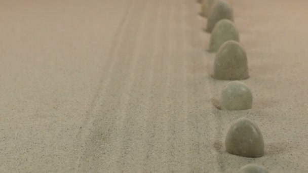 Приближение белых камней, стоящих на линиях из песка. Долли — стоковое видео