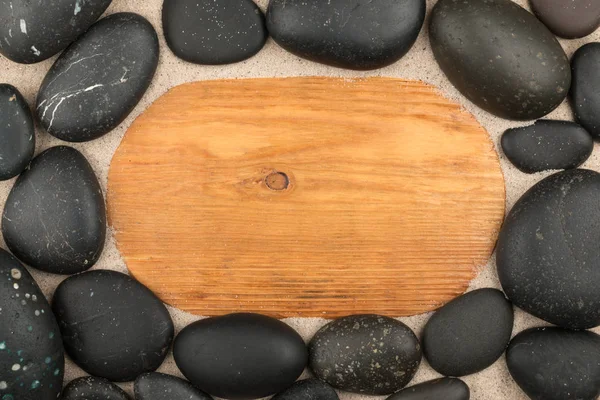 空框的轻木和黑色的石头在沙子。复制空间. — 图库照片