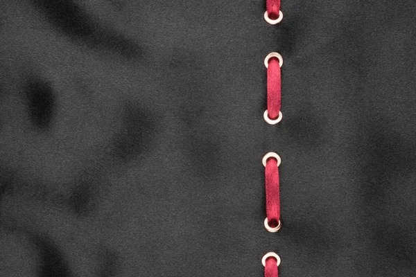 Pita merah dimasukkan ke dalam satin bergelombang hitam. Latar belakang yang indah . — Stok Foto