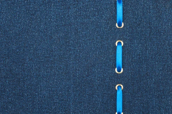 Синя атласна стрічка вставляється в темну джинсову тканину. Вид зверху . — стокове фото