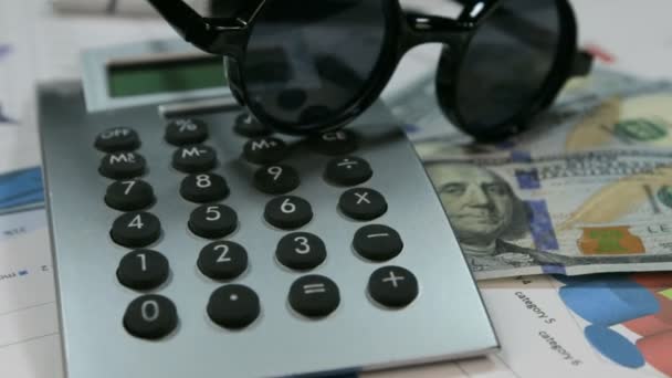 Lunettes hipster de protection solaire reposent sur la calculatrice et dollars. Rotation . — Video