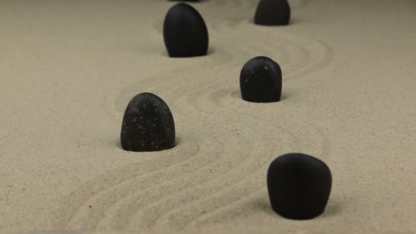 Inzoomen. Zwarte stenen liggend op het zand zigzag. — Stockvideo