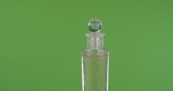 Primo piano, rotazione di una bottiglia di olio cosmetico su uno schermo verde . — Video Stock