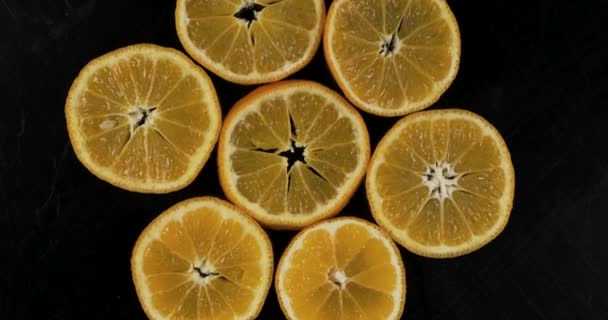 Samling av färska mandarin skivor på svart bakgrund. Rotationscitrusfrukter. Ovanifrån. — Stockvideo
