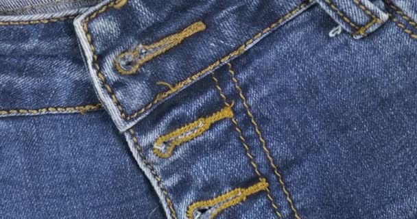 Rotation, Nahaufnahme, Detail der Blue Denim Jeans, Gürtelschlaufe von vorne, Tasche und Knopfloch. Modehintergrund. — Stockvideo