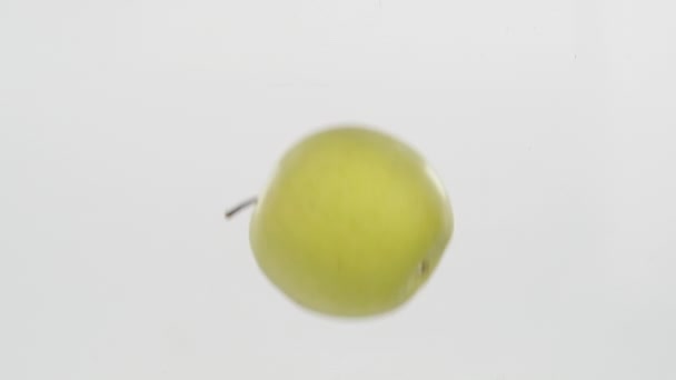 Langzame beweging. Groene appel die in het water valt en onder water drijft. — Stockvideo
