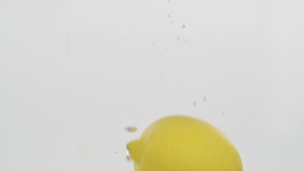 Sakta i backarna. Citron faller i vatten och flyter under vattnet. — Stockvideo