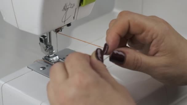 Preparación para la costura. La costurera inserta hilo en la aguja de una máquina de coser . — Vídeo de stock