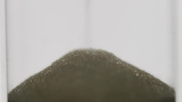 Slow motion, hourglass with falling yellow sand on white background. Macro close-up. — Stock Video
