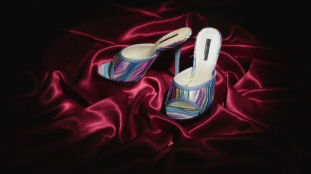Zoom.Two blue clogs with high heels and a platform on red crumpled fabric. — Stock Video