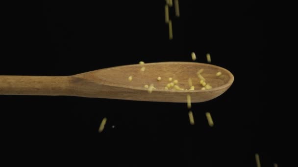 Falling grain millet fills the spoon and fall out of a wooden spoon. Slow motion. Close-up. — Stock Video