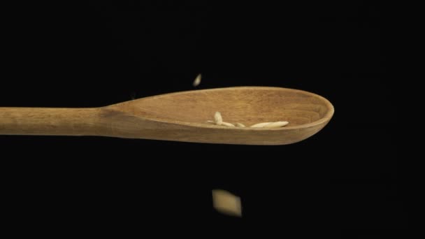 La avena de grano que cae llena la cuchara y se cae de una cuchara de madera. Movimiento lento . — Vídeo de stock