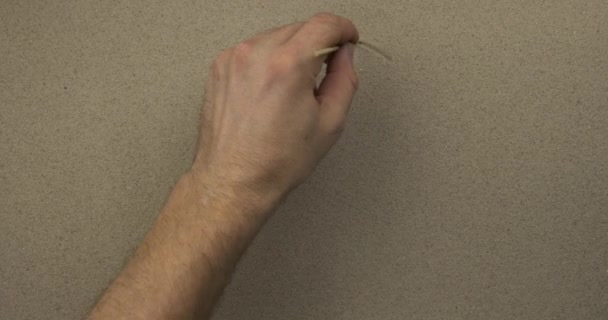 Male hand draws a happy symbolic face on the sand of a person. Top view. — Stock Video