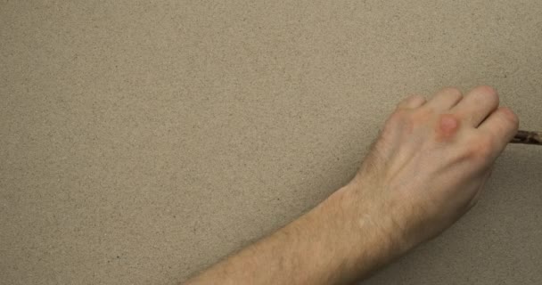 Αρσενικό χέρι σχεδιάζει ευθείες γραμμές στην άμμο. Άνω όψη. — Αρχείο Βίντεο