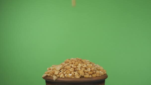 Зерна гороху потрапляють в переповнену глиняну миску і випадають з неї. Ізольовані на зеленому екрані . — стокове відео