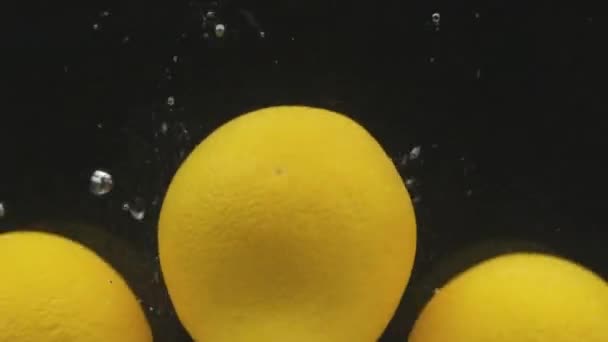 Whole oranges falls into the water with bubbles. Slow motion. — Stock Video