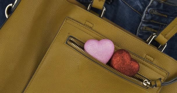 Zwei Herzen ragen aus der Tasche eines gelben Sacks für Frauen. Rotation. Hintergrund von Liebe und Mode. — Stockvideo