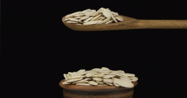 Pumpkin grains get enough sleep from a wooden spoon on a pile of seed in a clay bowl. — Stock Video