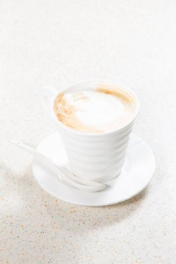 Tahta arka planda beyaz köpüklü bir fincan kahve