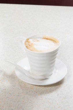 Tahta arka planda beyaz köpüklü bir fincan kahve