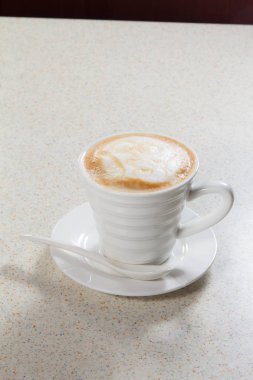 Tahta arka planda beyaz köpüklü bir fincan kahve
