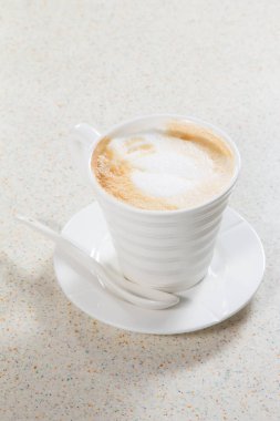 Tahta arka planda beyaz köpüklü bir fincan kahve