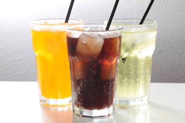 Beyaz arka planda buz küpleri olan bir bardak soğuk içecek.