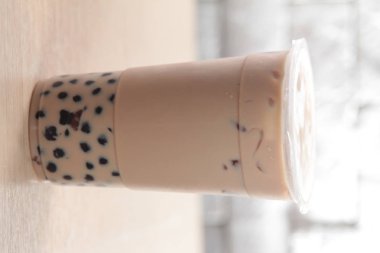 close up of a white cup of coffee on a wooden table