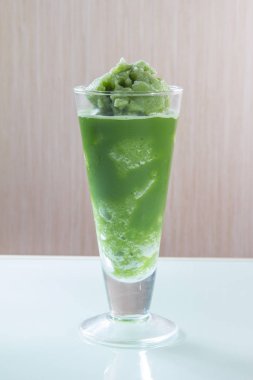 Beyaz arka planda cam bardakta yeşil içecek.