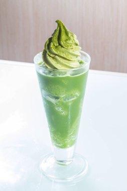 Beyaz arka planda cam bardakta yeşil içecek.