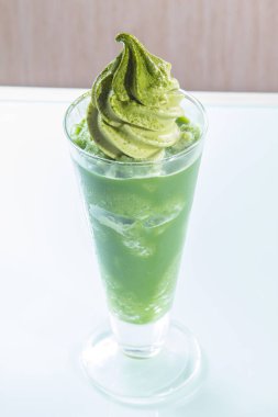 Beyaz arka planda cam bardakta yeşil içecek.