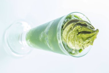 Beyaz arka planda cam bardakta yeşil içecek.