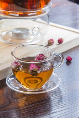 tea in a glass cup and dried  flowers on a wooden table