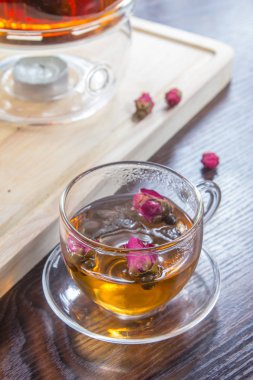 tea in a glass cup and dried  flowers on a wooden table
