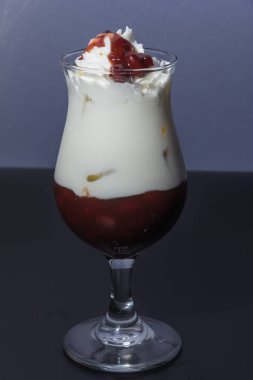 glass of tasty dessert with whipped cream and chocolate on a dark background