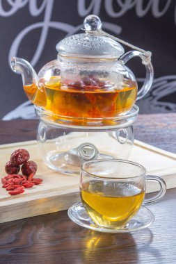 glass teapot, tea in a glass cup and dried  flowers on a wooden table