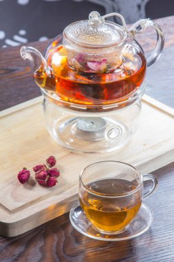 glass teapot, tea in a glass cup and dried  flowers on a wooden table