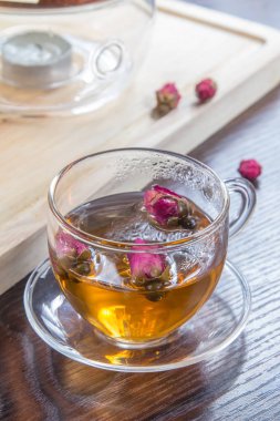 tea in a glass cup and dried  flowers on a wooden table