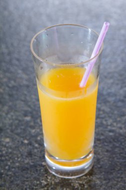orange juice and fruit smoothie on a background of glass with straws on the table.