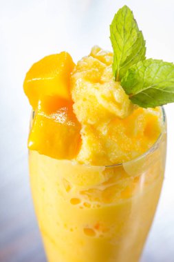 Tahta bir masada, bardakta mango suyu.