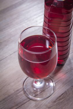 Arka planda böğürtlen olan bir bardak kırmızı içki.