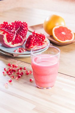 Nar ve ahşap zemin üzerinde greyfurt ile taze meyve suyu