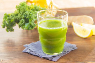 yeşil meyve suyu ve ahşap arka planda zencefil.