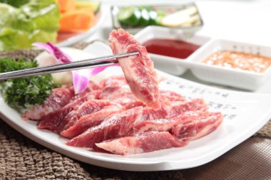 Arka planda baharatlı ve çubuklu çiğ et, yakın plan.