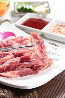 Arka planda baharatlı ve çubuklu çiğ et, yakın plan.