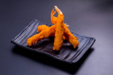 Siyah arka planda soslu kızarmış balık.